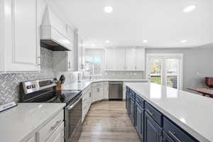 Kitchen with stainless steel appliances, two tone cabinetry, light wood finished floors, light stone counters, and recessed lighting