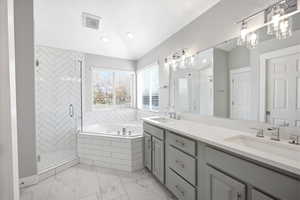 Full bathroom featuring a stall shower, double vanity, and a garden tub