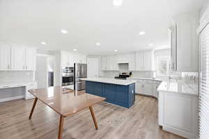 Dual tone kitchen with a kitchen island, dual tone cabinetry, light wood-style flooring, stainless steel appliances, and recessed lighting