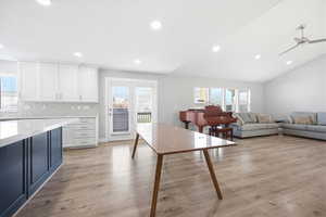 Two tone kitchen featuring two tone cabinetry, ceiling fan, light wood finished floors, healthy amount of natural light, and tasteful backsplash