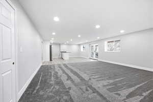 Below grade area with light carpet, recessed lighting, and freestanding refrigerator