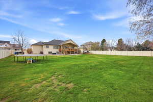 Fenced backyard featuring a trampoline and a patio