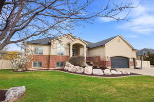 View of front of property featuring brick siding, concrete driveway, a garage, and stucco siding