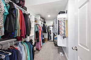 Walk in closet with light colored carpet