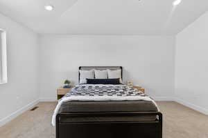 Bedroom with light colored carpet, recessed lighting, and lofted ceiling