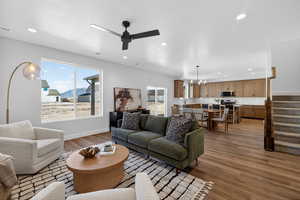 Living room featuring dark wood-style flooring, a ceiling fan, suspended lighting, and healthy amount of natural light