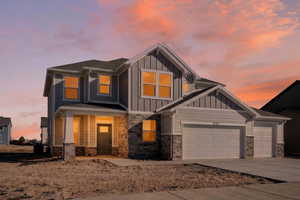 Craftsman house featuring stone siding, board and batten siding, a garage, and driveway