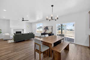 Dining space featuring ceiling fan, wood finished floors, a fireplace, and suspended lighting