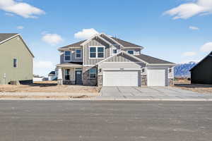 Craftsman-style house with an attached garage, stone siding, board and batten siding, and concrete driveway