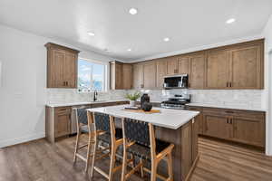 Kitchen featuring a breakfast bar, stainless steel appliances, light wood-style floors, a center island, and recessed lighting