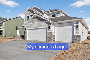 Craftsman-style home with board and batten siding, driveway, stone siding, and a shingled roof