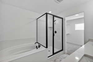 Full bathroom featuring vanity, a stall shower, a bath, and light marble finish floors