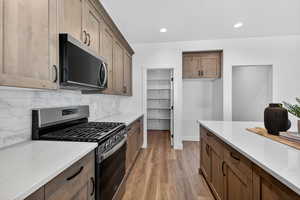 Kitchen featuring stainless steel appliances, light stone countertops, light wood-style floors, recessed lighting, and wood finish cabinets