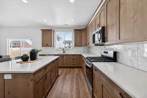 Kitchen featuring stainless steel appliances, light wood finished floors, wood finish cabinetry, decorative backsplash, and recessed lighting