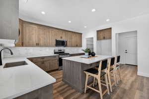 Kitchen featuring light stone countertops, stainless steel appliances, a kitchen island, dark wood-style floors, and recessed lighting