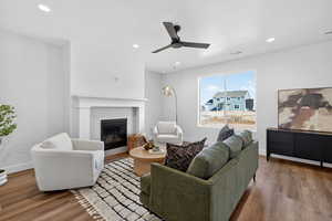 Living room with wood finished floors, a ceiling fan, recessed lighting, and a tile fireplace