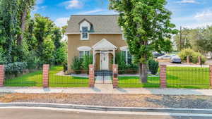 View of front of house with roof with shingles, stucco siding, a fenced front yard, and a gate
