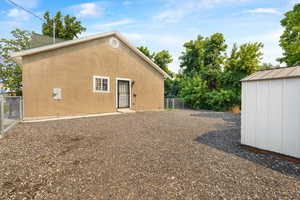 View of side of home featuring stucco siding and a storage shed