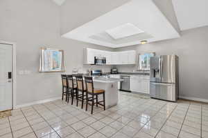 Kitchen with a kitchen bar, a tray ceiling, stainless steel appliances, a peninsula, and white cabinets