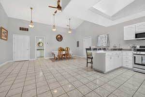 Kitchen featuring a breakfast bar, stainless steel range with electric stovetop, a peninsula, white cabinetry, and decorative light fixtures