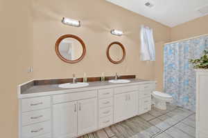 Full bathroom featuring double vanity, light tile patterned floors, and a shower with curtain