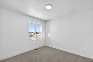 Unfurnished room with dark colored carpet and a textured ceiling