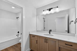 Full bathroom with vanity, dark wood-style flooring, shower / tub combination, and recessed lighting