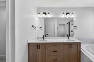Bathroom featuring double vanity, a shower stall, and a bath