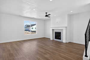 Unfurnished living room featuring ceiling fan, dark wood-style floors, recessed lighting, a tile fireplace, and a textured ceiling
