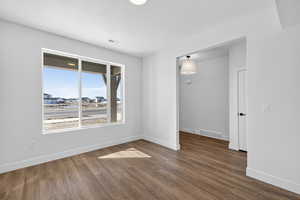 Spare room with baseboards and dark wood-style flooring