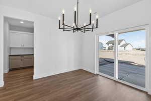 Unfurnished dining area with dark wood-style floors and suspended lighting