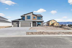 Modern home featuring a standing seam roof, stone siding, driveway, a garage, and a mountain view