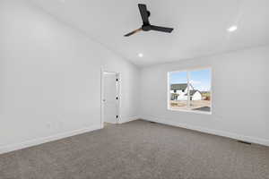 Empty room with lofted ceiling, dark carpet, a ceiling fan, and recessed lighting