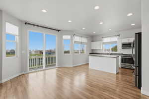 Kitchen featuring stainless steel appliances, white cabinetry, recessed lighting, light wood finished floors, and a kitchen island