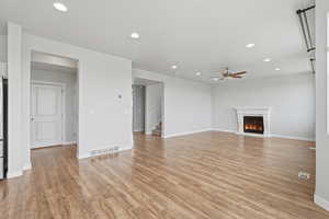 Unfurnished living room with a glass covered fireplace, recessed lighting, light wood-type flooring, and a ceiling fan