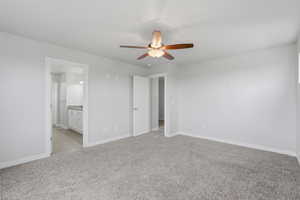Unfurnished bedroom with light carpet, ceiling fan, and ensuite bathroom