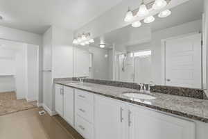 Bathroom featuring double vanity, a stall shower, a spacious closet, and light tile patterned floors