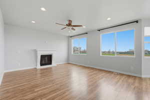 Unfurnished living room with recessed lighting, ceiling fan, light wood finished floors, and a glass covered fireplace