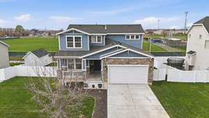 View of front facade featuring a shingled roof, a residential view, driveway, and stone siding