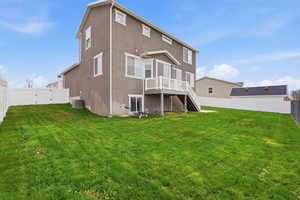 Rear view of house with a fenced backyard, a gate, a deck, and stucco siding