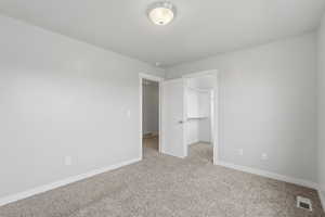 Unfurnished bedroom with a spacious closet and light colored carpet