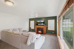 Carpeted living room featuring a fireplace with flush hearth and baseboards
