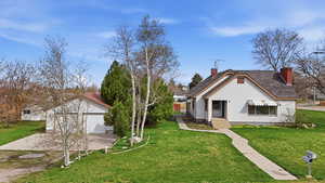 View of front of home featuring a front lawn, a chimney, a garage, and driveway