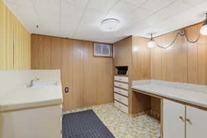 Bathroom with vanity, wood walls, and light flooring