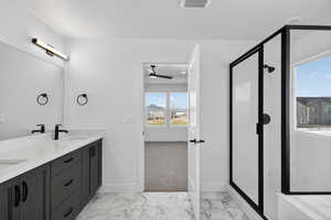 Bathroom featuring light marble finish floors, a shower stall, double vanity, and a ceiling fan