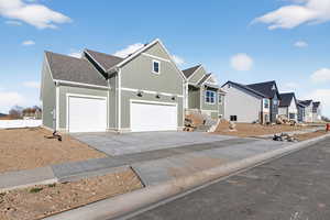 View of front of house with concrete driveway, a shingled roof, an attached garage, a residential view, and board and batten siding