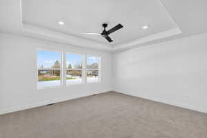 Unfurnished room with carpet flooring, a ceiling fan, a tray ceiling, and recessed lighting