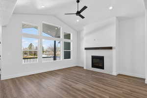 Unfurnished living room featuring ceiling fan, a high ceiling, dark wood-type flooring, a tiled fireplace, and recessed lighting