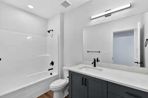 Full bath featuring vanity, washtub / shower combination, and dark wood-style flooring