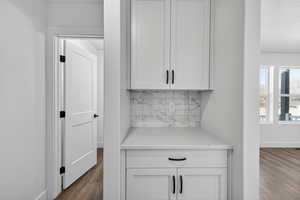 Detailed view of wood finished floors, a textured ceiling, and decorative backsplash